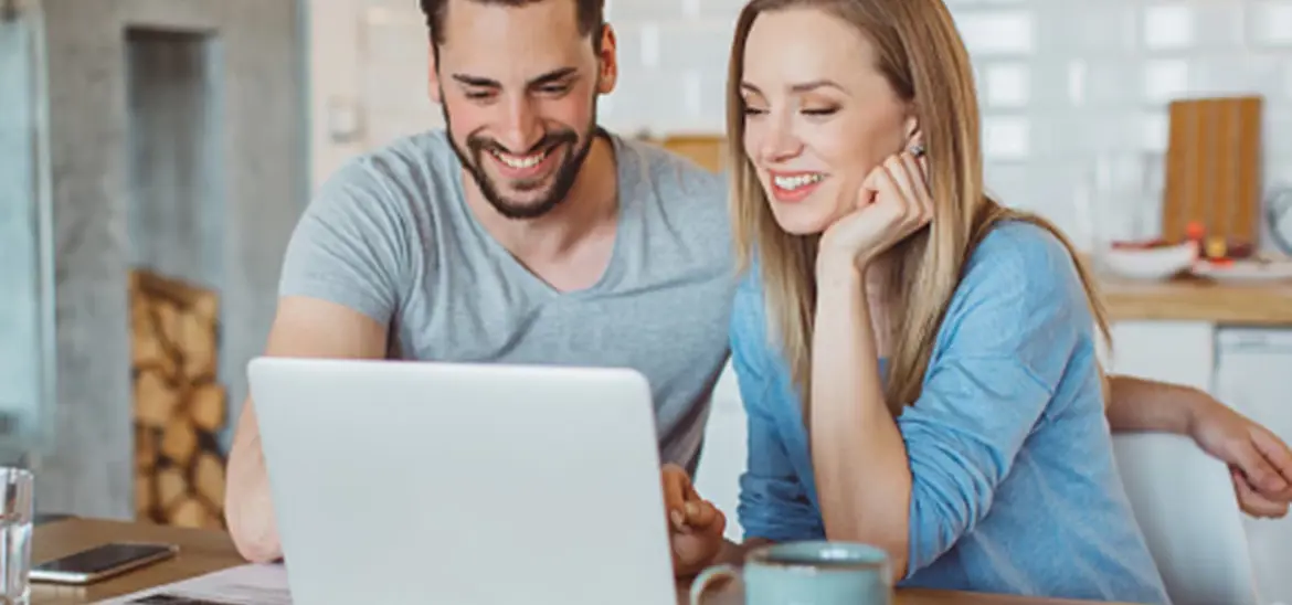 A smiling couple looking at a laptop screen