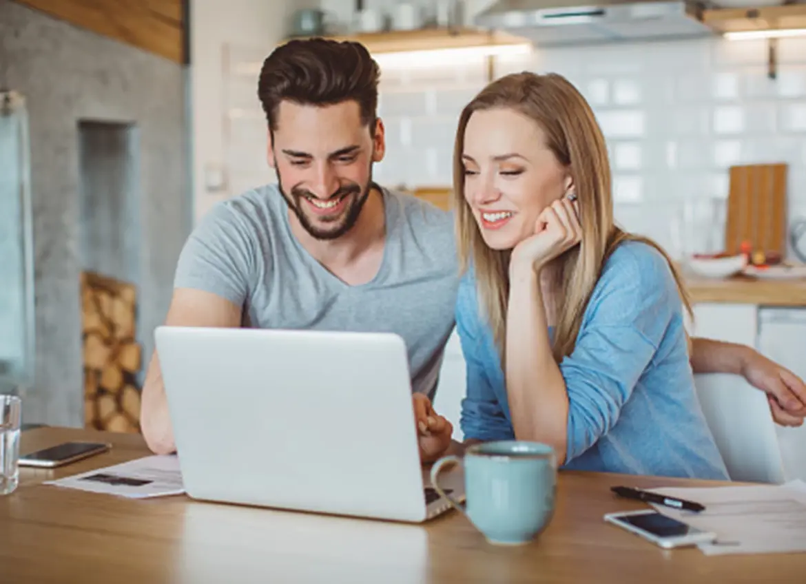 A smiling couple looking at a laptop screen