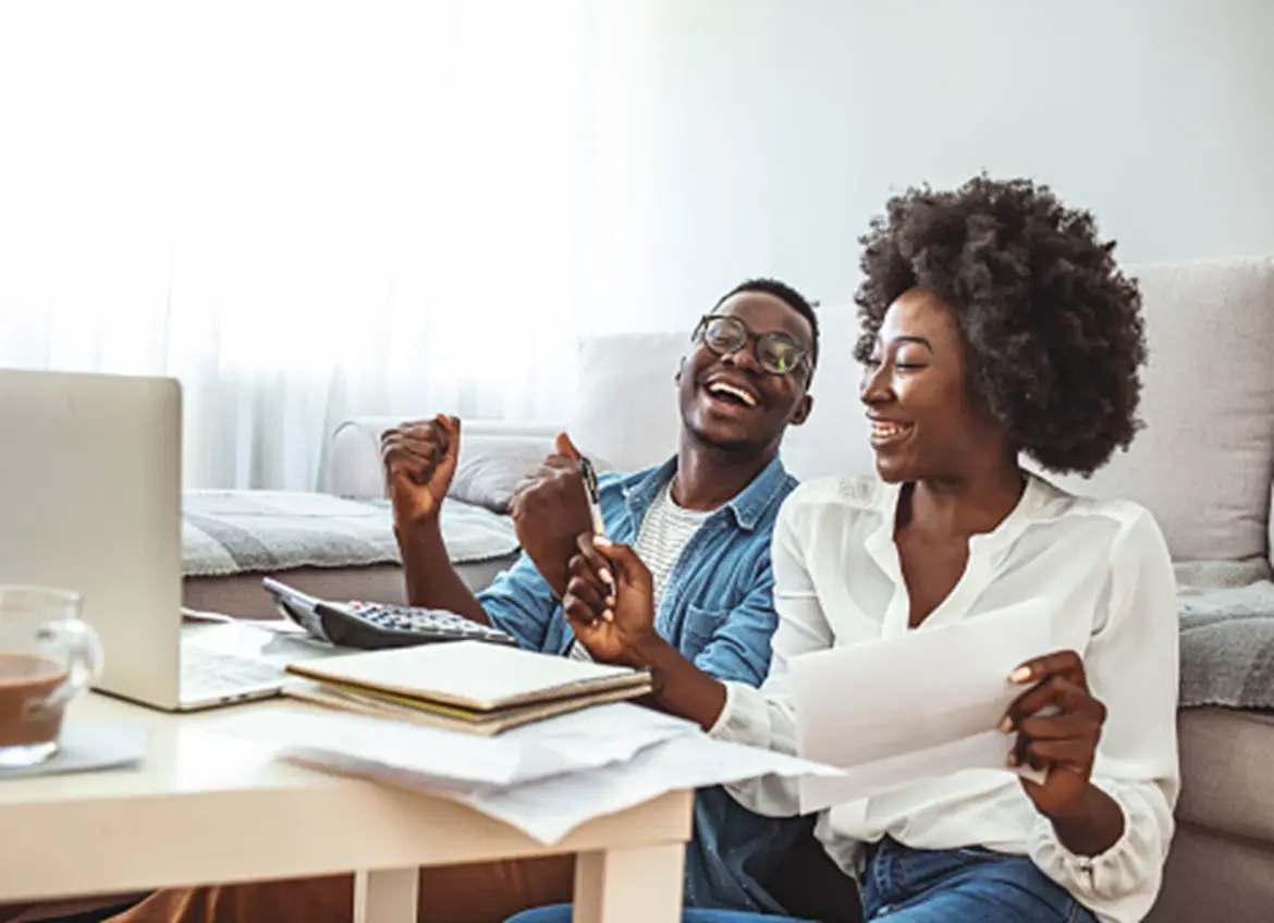 A happy couple cheering while reviewing paperwork