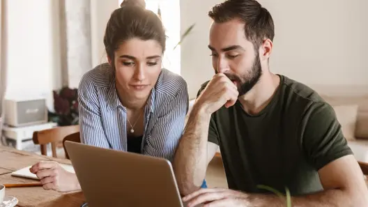 A couple carefully reviewing information on their laptop