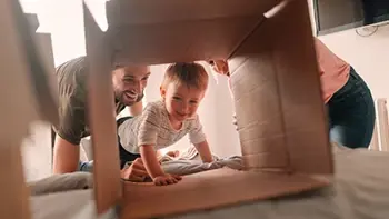 A baby crawling in a box, playing with his parents