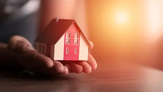 A person holding a miniature home in his hand