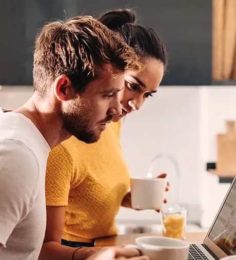 Couple looking at laptop while drinking coffee