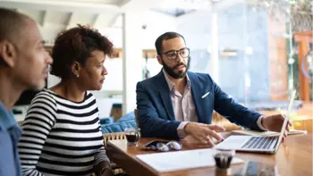 A couple and a sales agent discussing while reviewing information on the agent's laptop