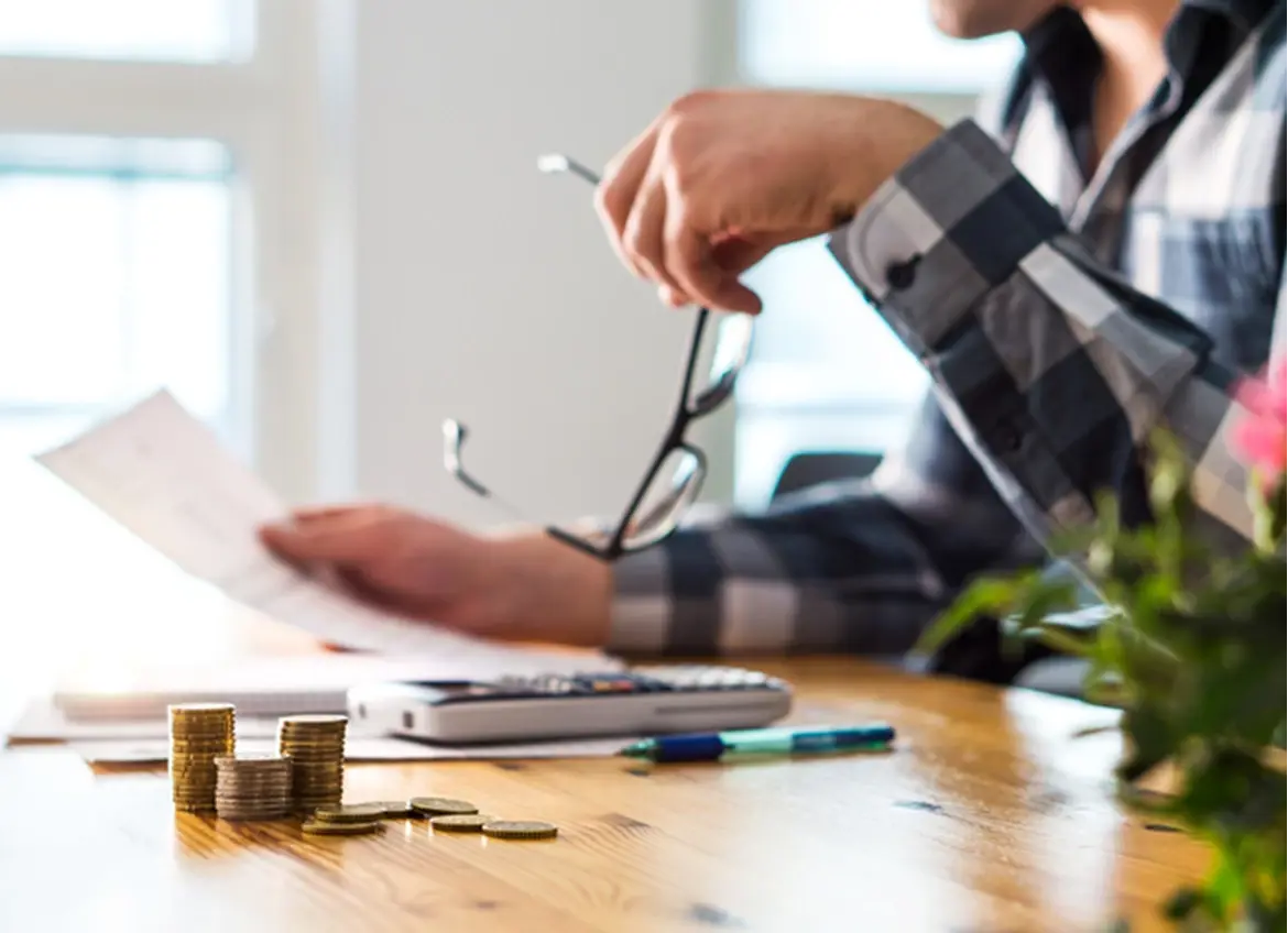 A man reviewing bills while holding his glasses in another hand