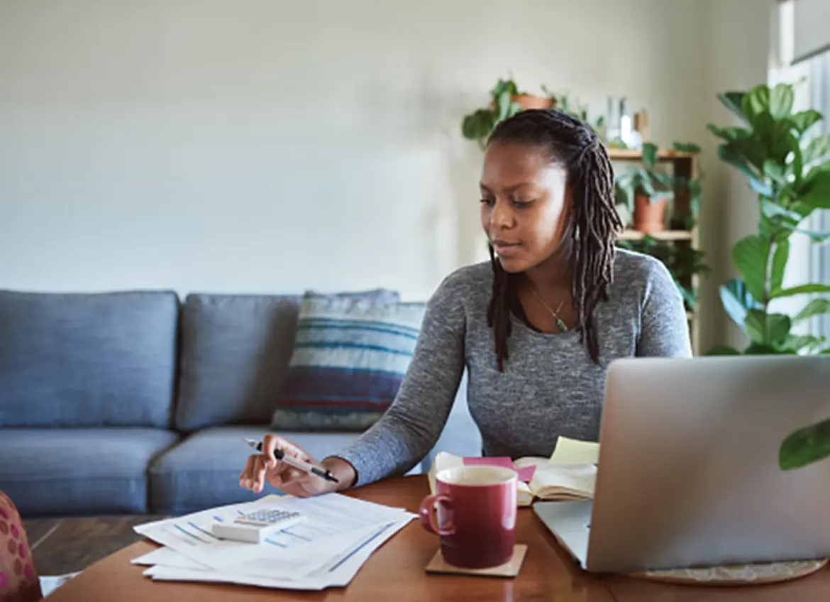 A woman using a calculator while reviewing bills