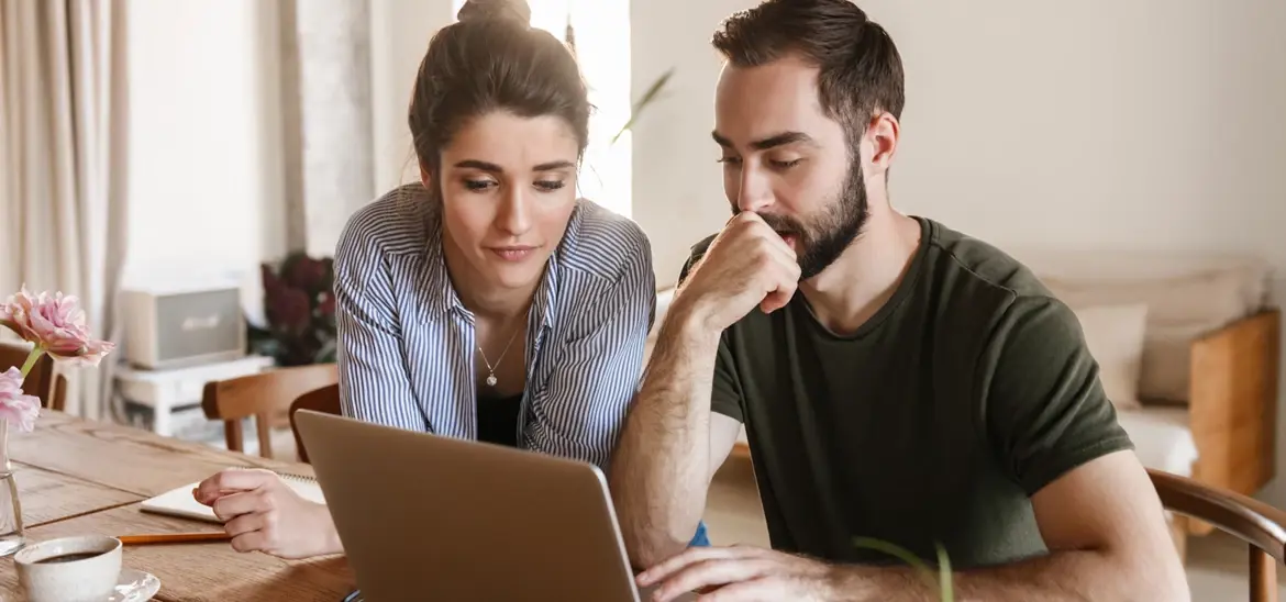 A couple carefully looking at a laptop screen