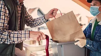 A person donating a bag of goods to an organization