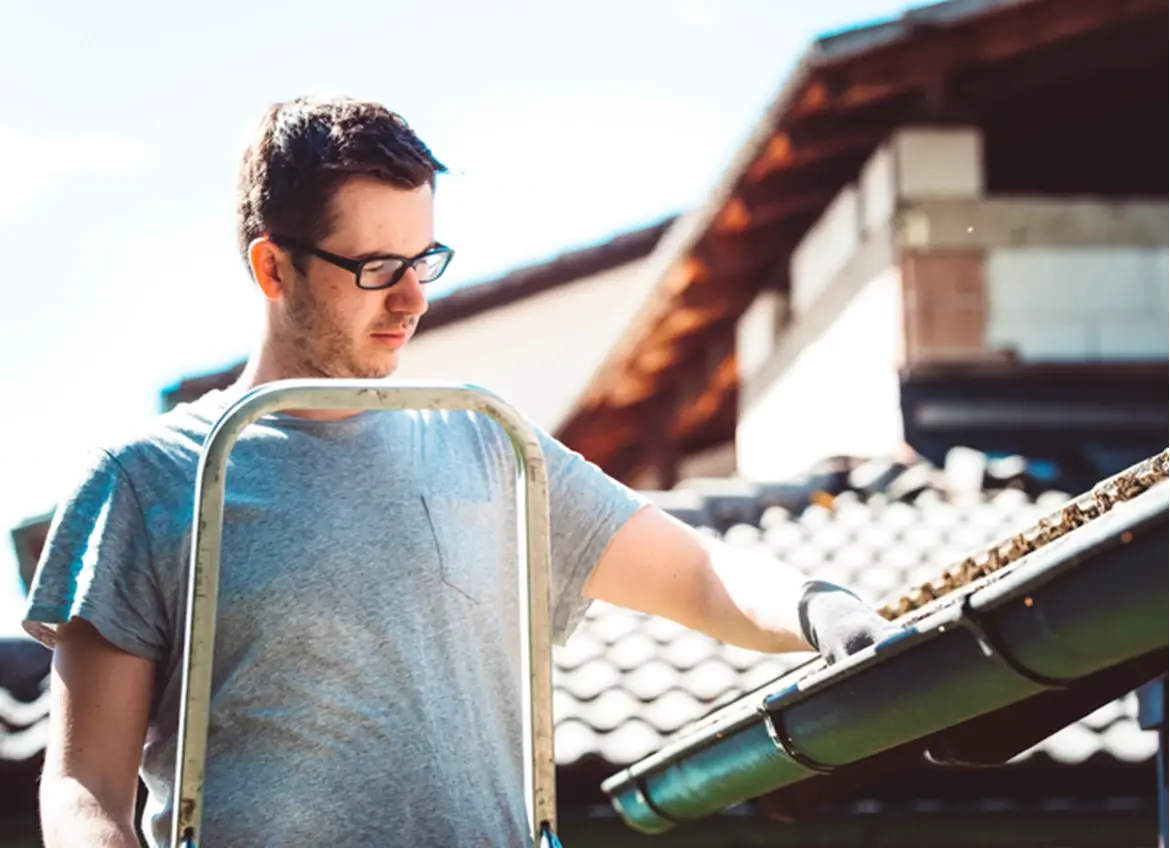 A man clearing out house gutters