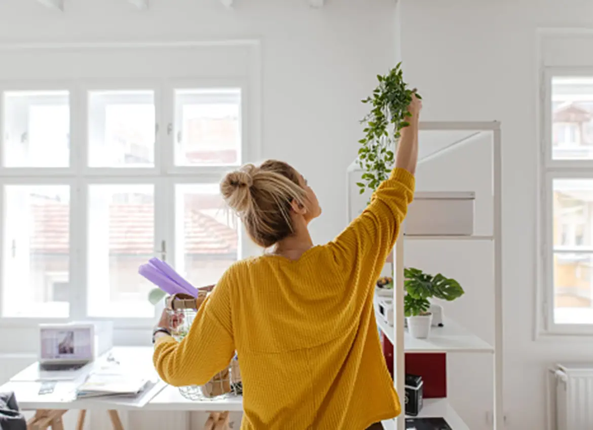 A woman putting plants up on a shelf