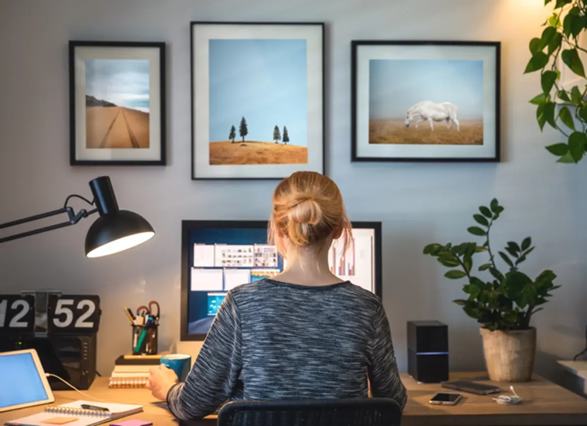 A woman at her desk using a computer, surrounded by personal photographs displayed on the wall