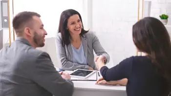 A representative in a meeting with customers, shaking hands with one of them