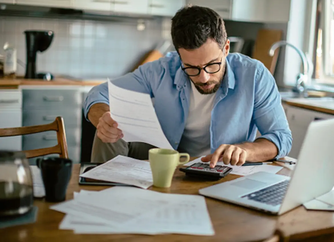 A man using a calculator while reviewing bills