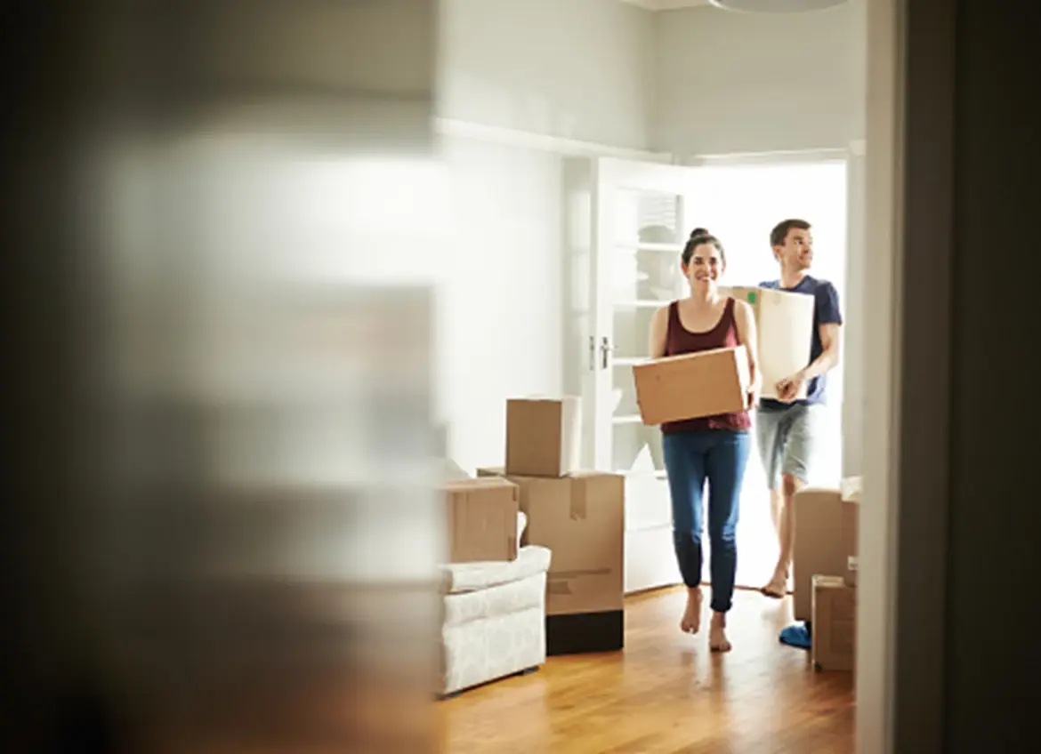 A couple moving into a new home carrying boxes