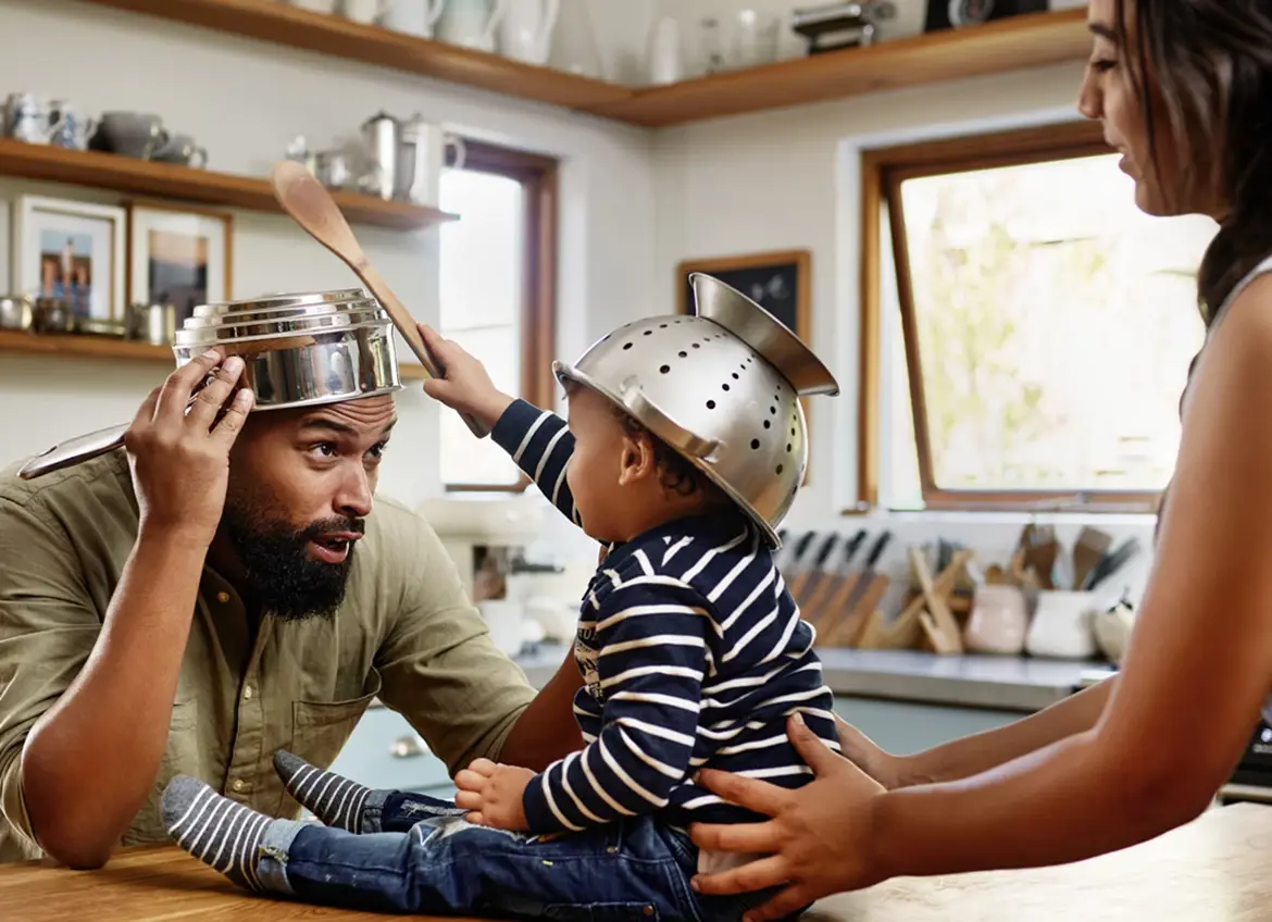 A family with baby playing in the kitchen with kitchen tools