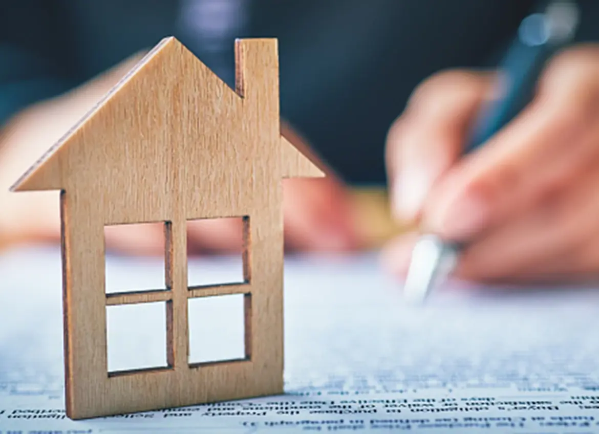 A House figurine sitting on a paperwork