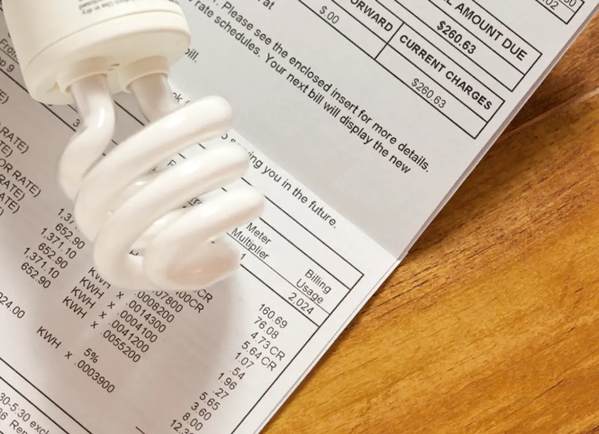 A fluorescent light bulb over an electric bill statement