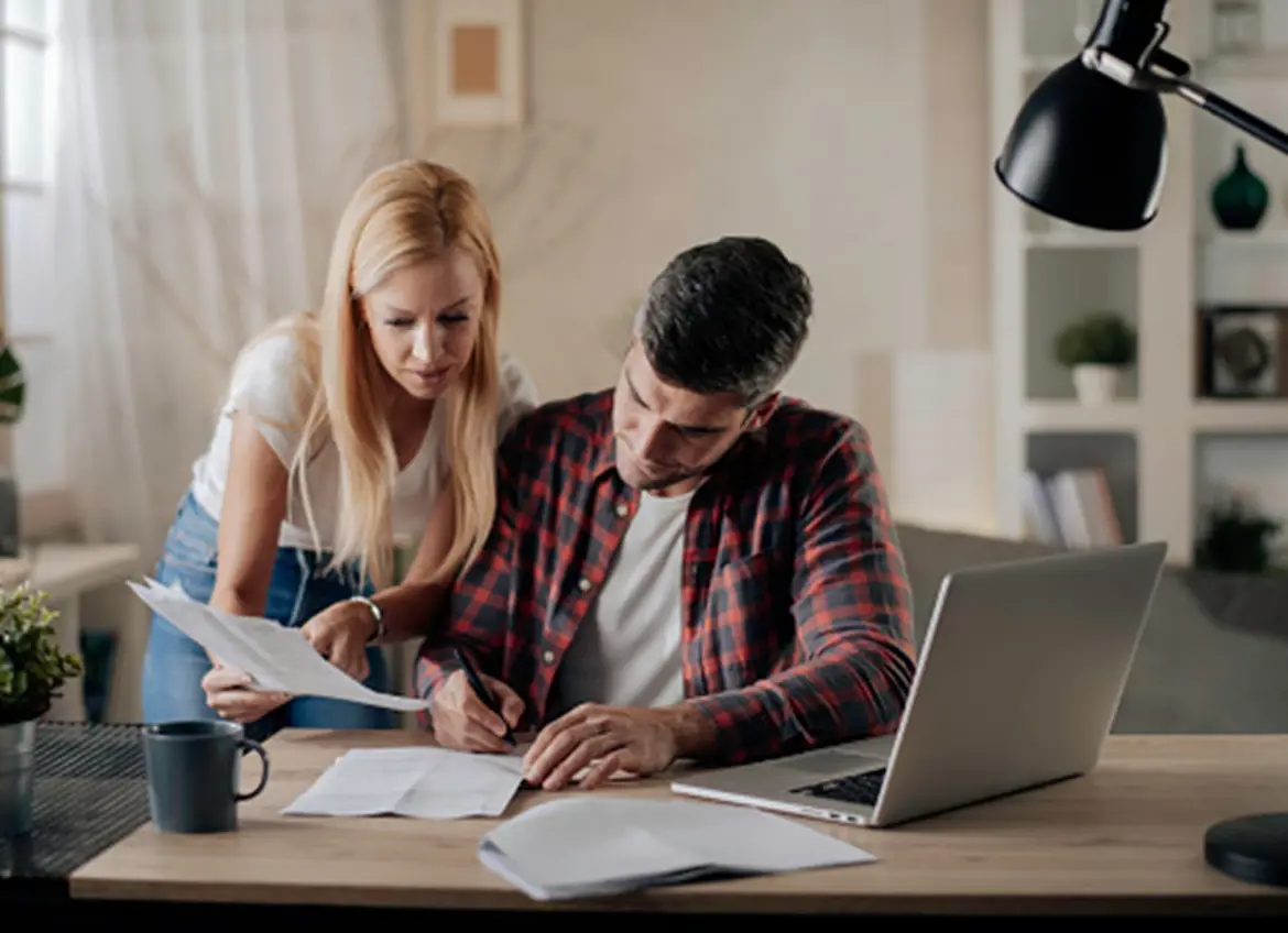 A couple carefully reviewing and signing paperwork