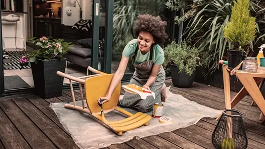 woman painting a chair outdoor