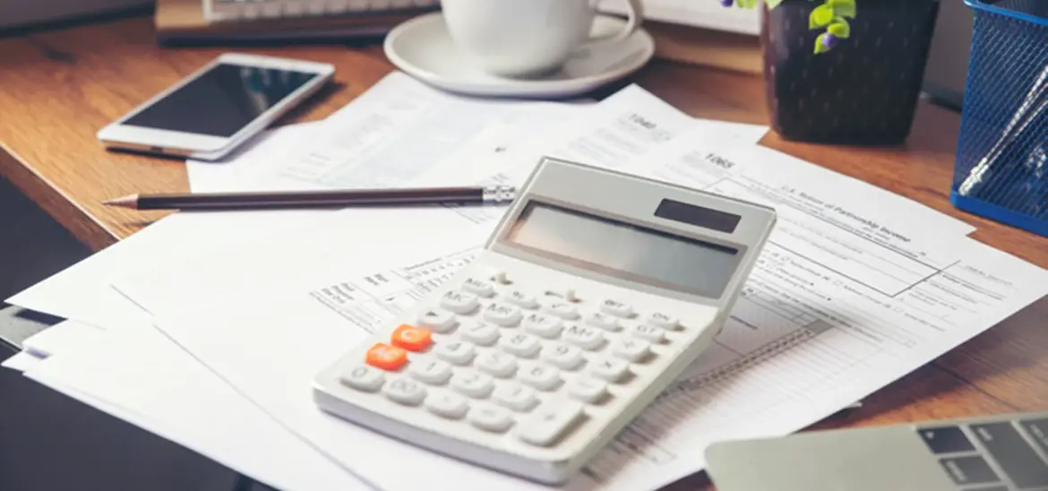 calculator and pencil on top of tax paperwork