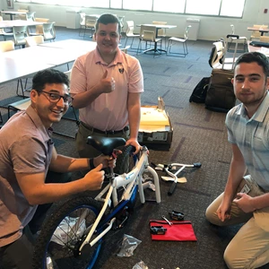 3 male interns building bike