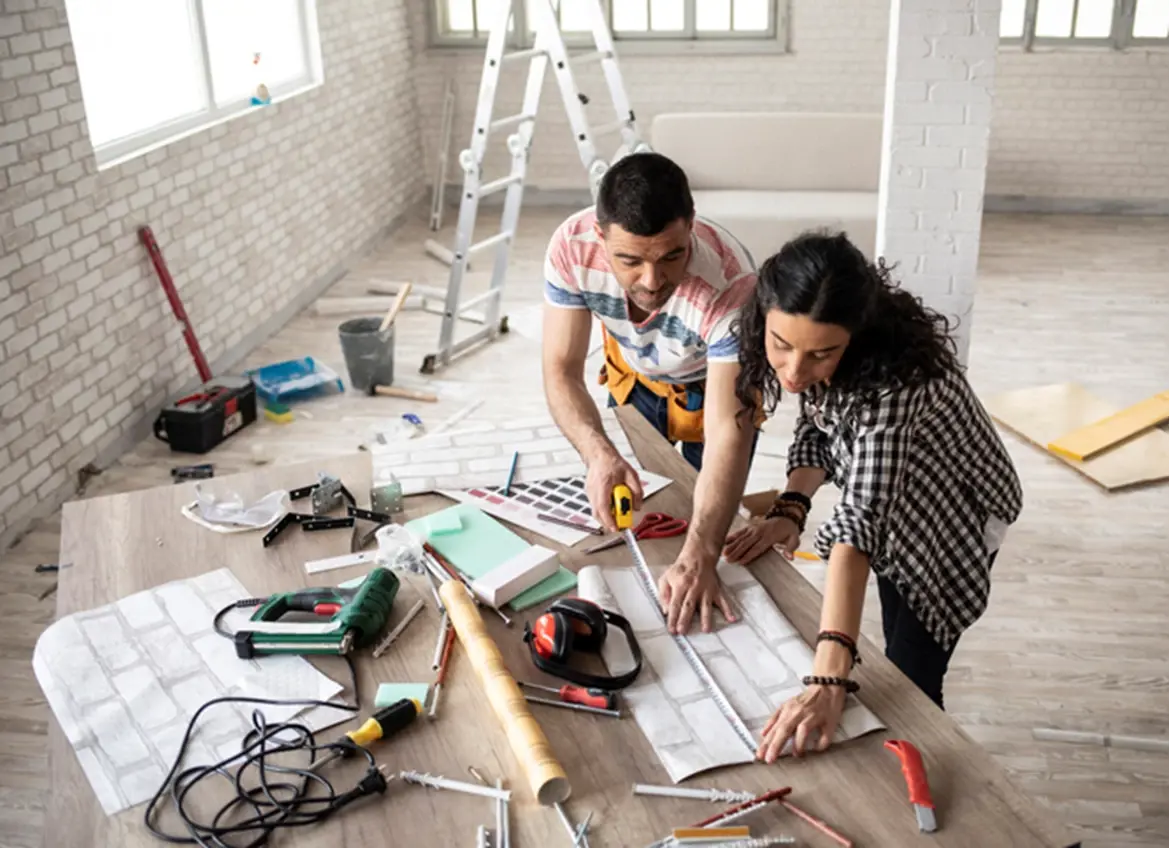 A couple working on wallpaper for a building